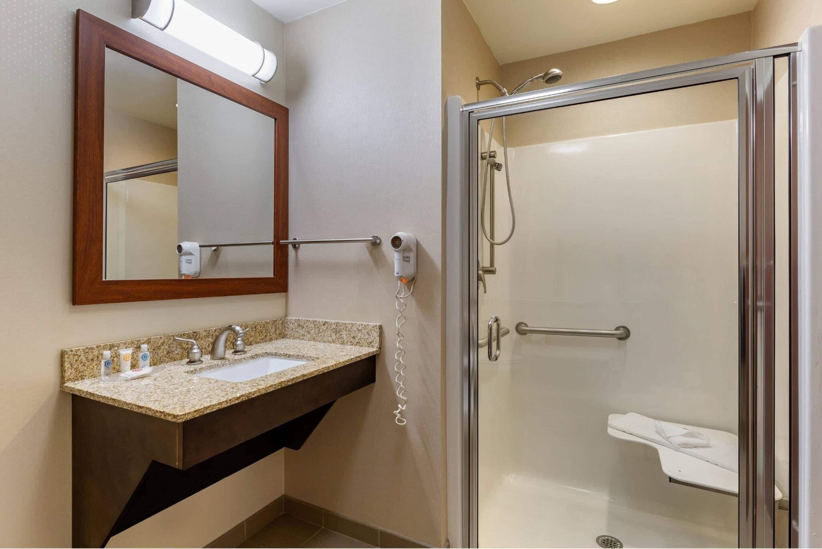 A bathroom with a sink, mirror, towel rack, and a glass-enclosed shower.