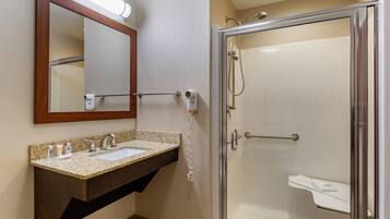 A bathroom with a sink, mirror, towel rack, and a glass-enclosed shower.