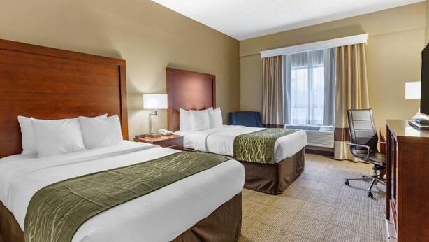A hotel room with two beds, a desk, a chair, a TV, and a window with curtains. - Comfort Inn Aikens Center (Martinsburg)