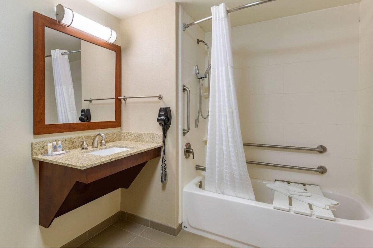 A bathroom with a sink, mirror, and shower.