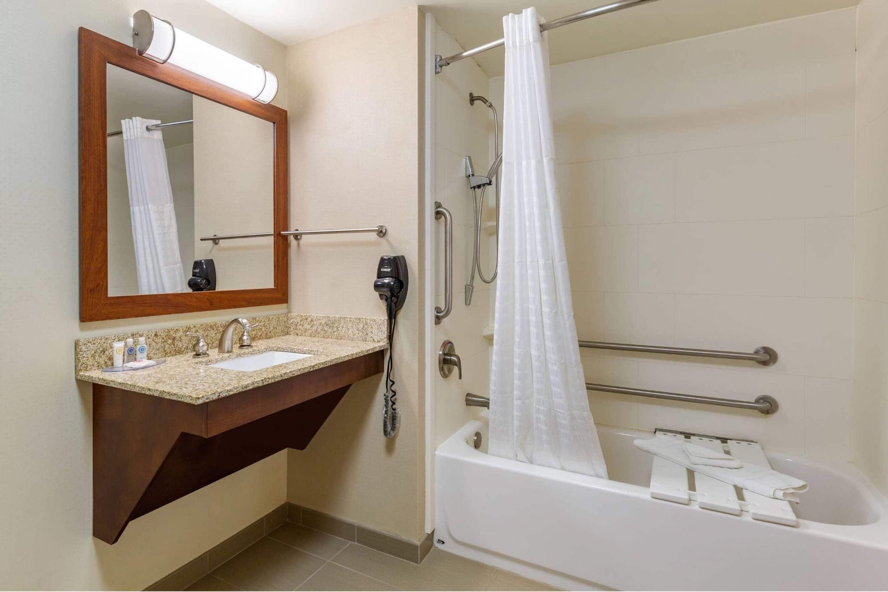 A bathroom with a sink, mirror, shower, and bathtub.