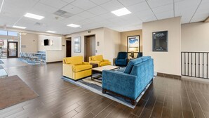A spacious lobby with a wooden floor, yellow and blue sofas, a coffee table, and a reception desk. - Comfort Inn Aikens Center (Martinsburg)