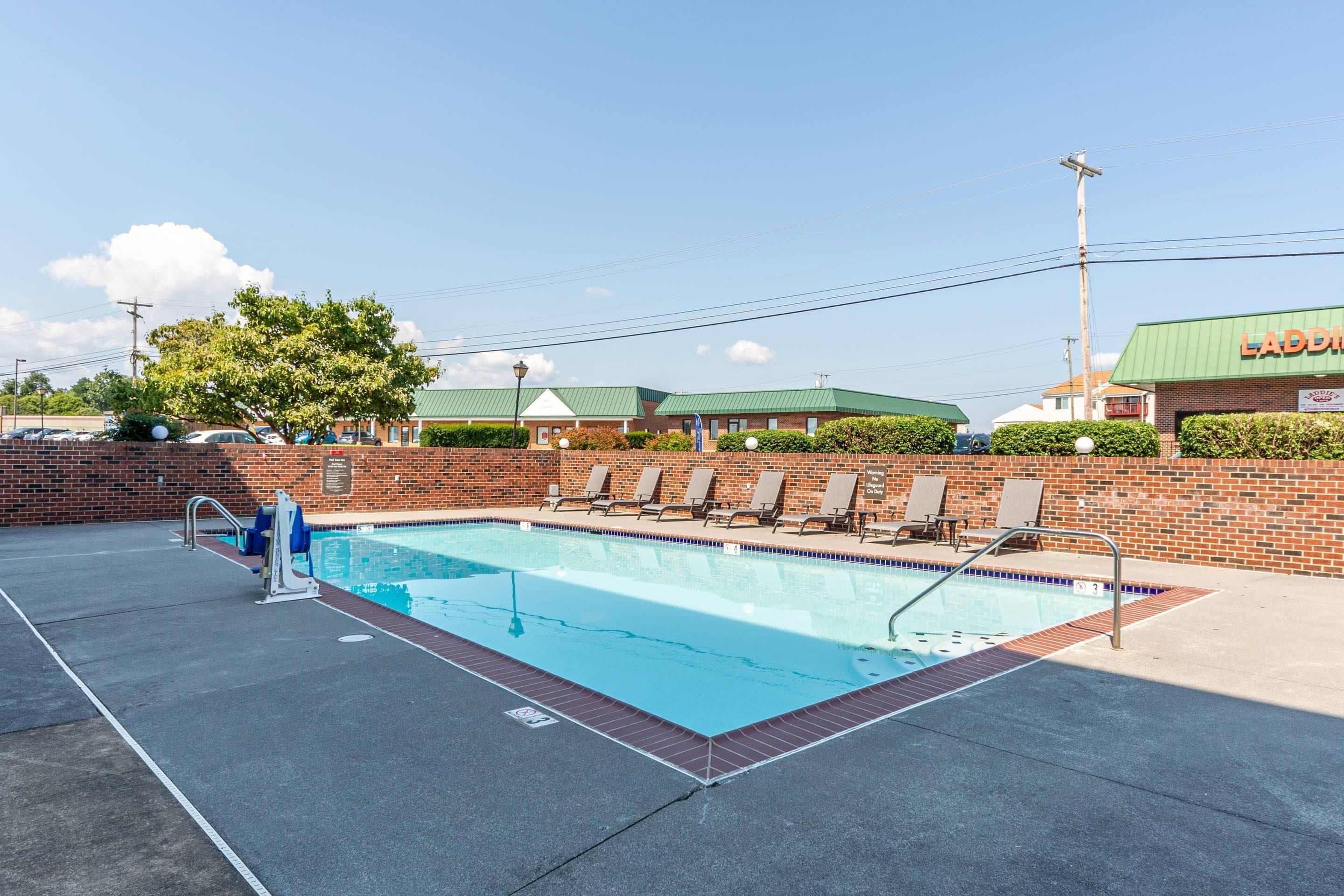 A swimming pool with lounge chairs and a brick wall.