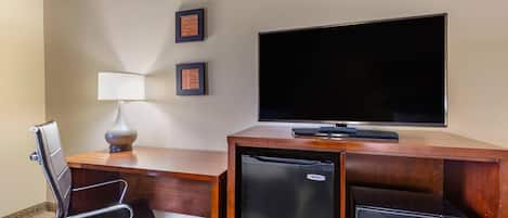 Ein Hotelzimmer mit Schreibtisch, Fernseher, Kühlschrank und Mikrowelle.