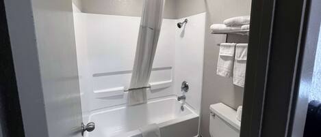 A bathroom with a bathtub, shower, toilet, and towel rack.