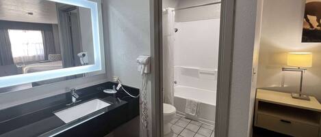 A bathroom with a black sink, a mirror, a toilet, and a shower.