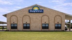 A Days Inn building with a clear blue sky and a grassy lawn in front.