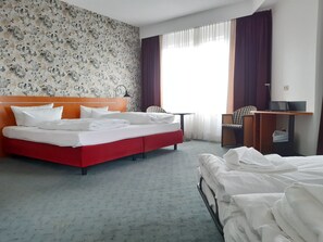 A hotel room with a bed, a desk, and a chair.
