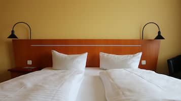 Cama doble con cabecera de madera, dos mesitas de noche y dos lámparas de escritorio negras.