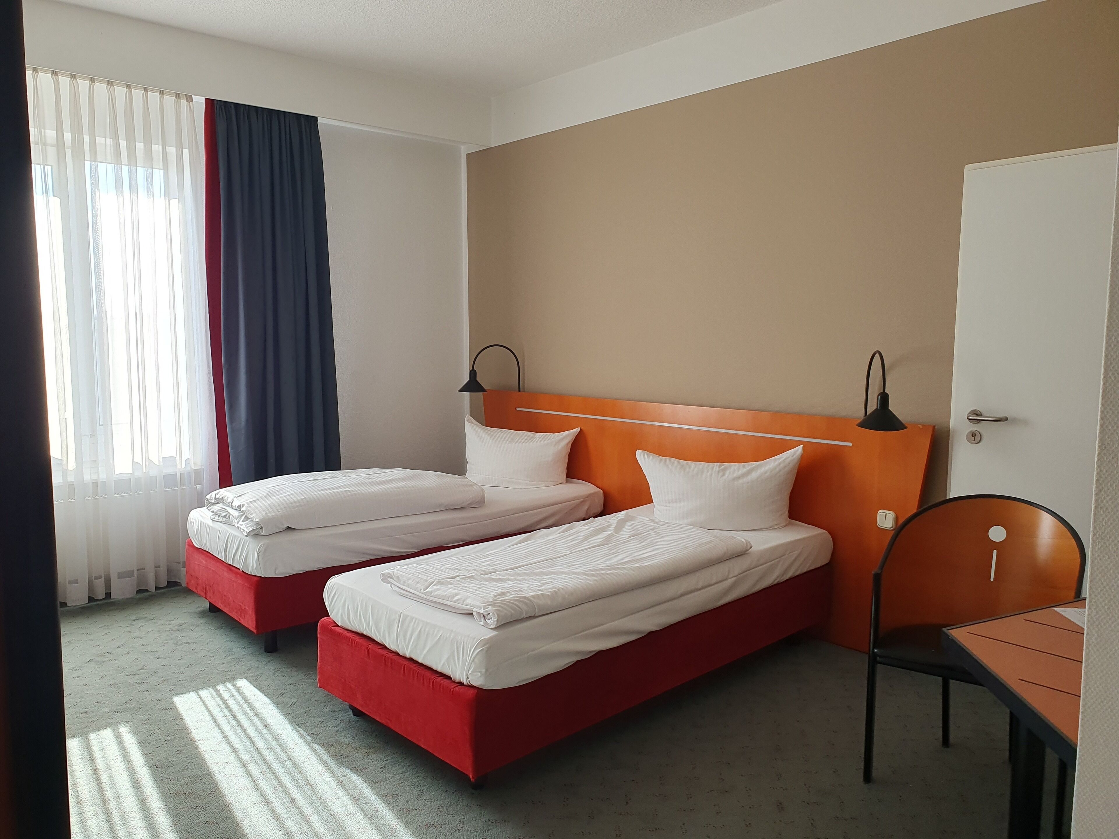 Una habitación de hotel con dos camas individuales, un escritorio y una silla.