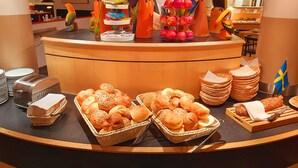 A buffet counter with various food items, including bread and pastries, and decorative parrot sculptures.