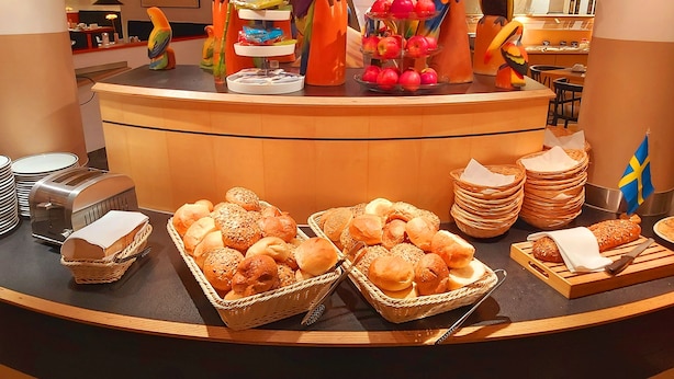 Un comptoir de buffet proposant une variété d’aliments, notamment du pain et des pâtisseries, ainsi que des sculptures décoratives représentant des perroquets.