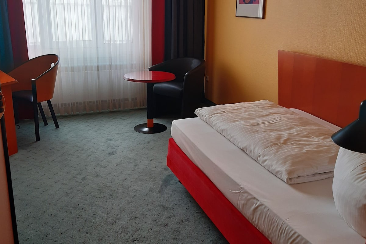 Ein Hotelzimmer mit Bett, Schreibtisch, Stuhl und einem kleinen Tisch.