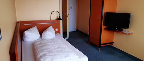 Una habitación de hotel con una cama, televisión y armario.