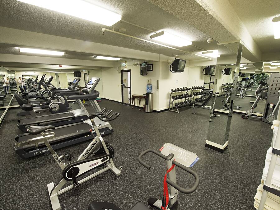 Un gimnasio con cintas de correr, bicicletas estáticas y máquinas de pesas.
