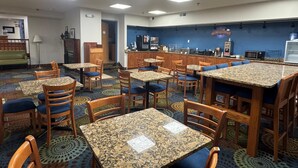 A restaurant with multiple tables and chairs, a kitchen area, and a counter.