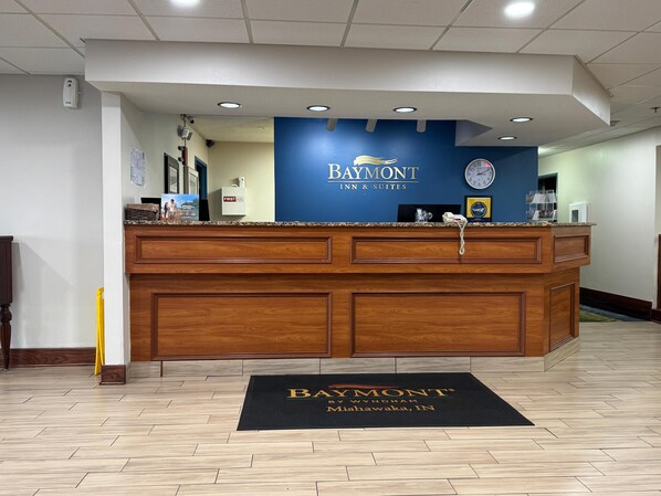 A reception desk with a blue wall and a clock.