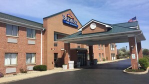 A Baymont Inn & Suites with a brick facade, a covered entrance, and an American flag.