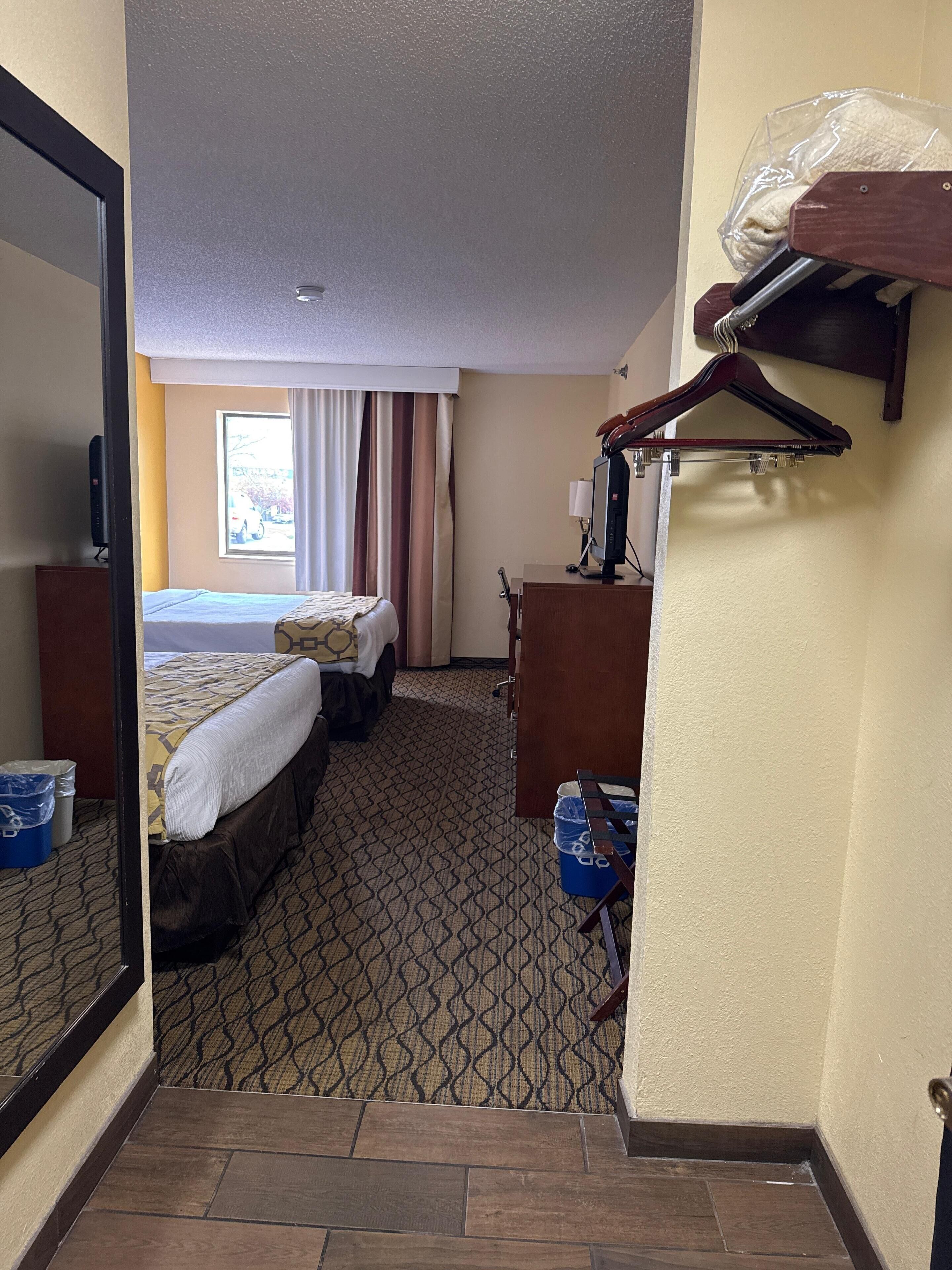 A hotel room with a bed, a desk, a chair, a TV, and a window with curtains.