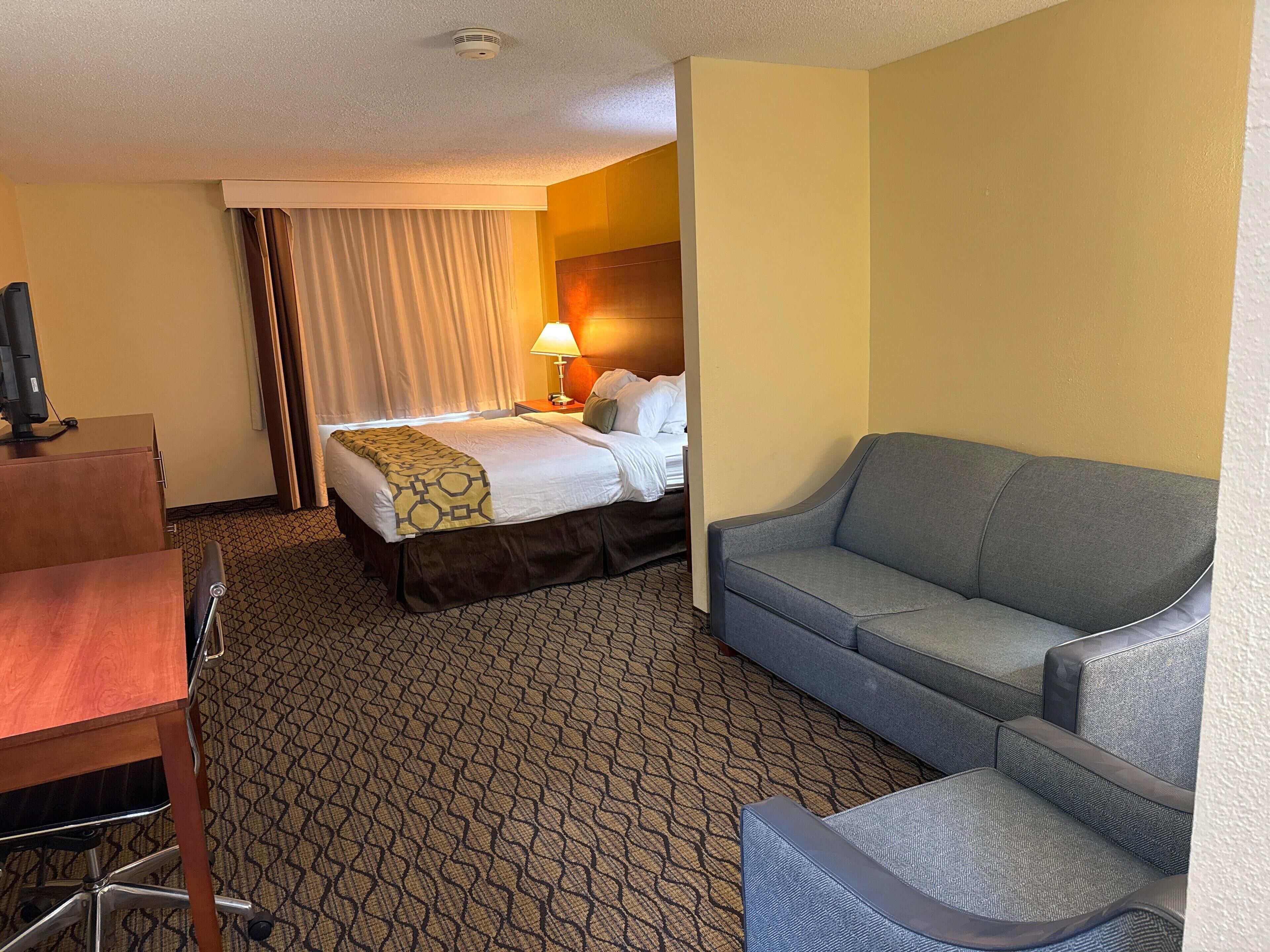 Una habitación de hotel con cama, sofá, escritorio y lámpara.