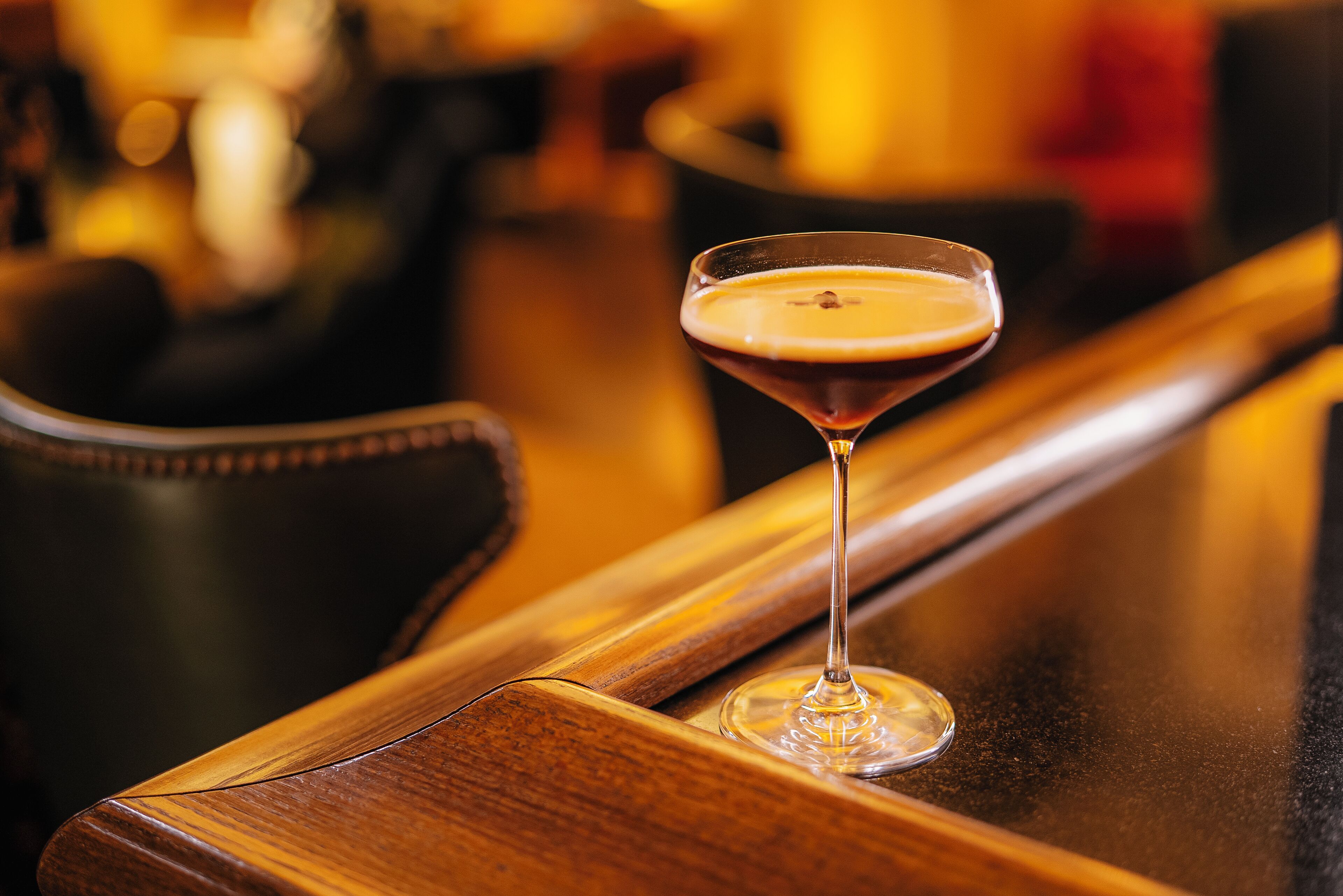 A martini glass on a wooden bar counter.