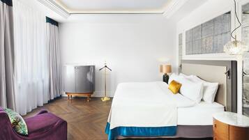 A hotel room with a bed, a dresser, a chair, a floor lamp, and a window with curtains.