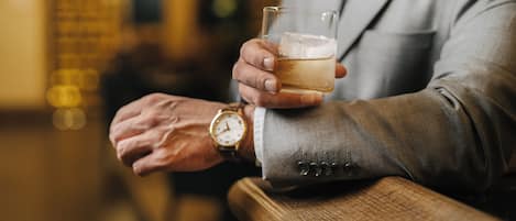 A person in a suit holding a glass of beer, wearing a watch.