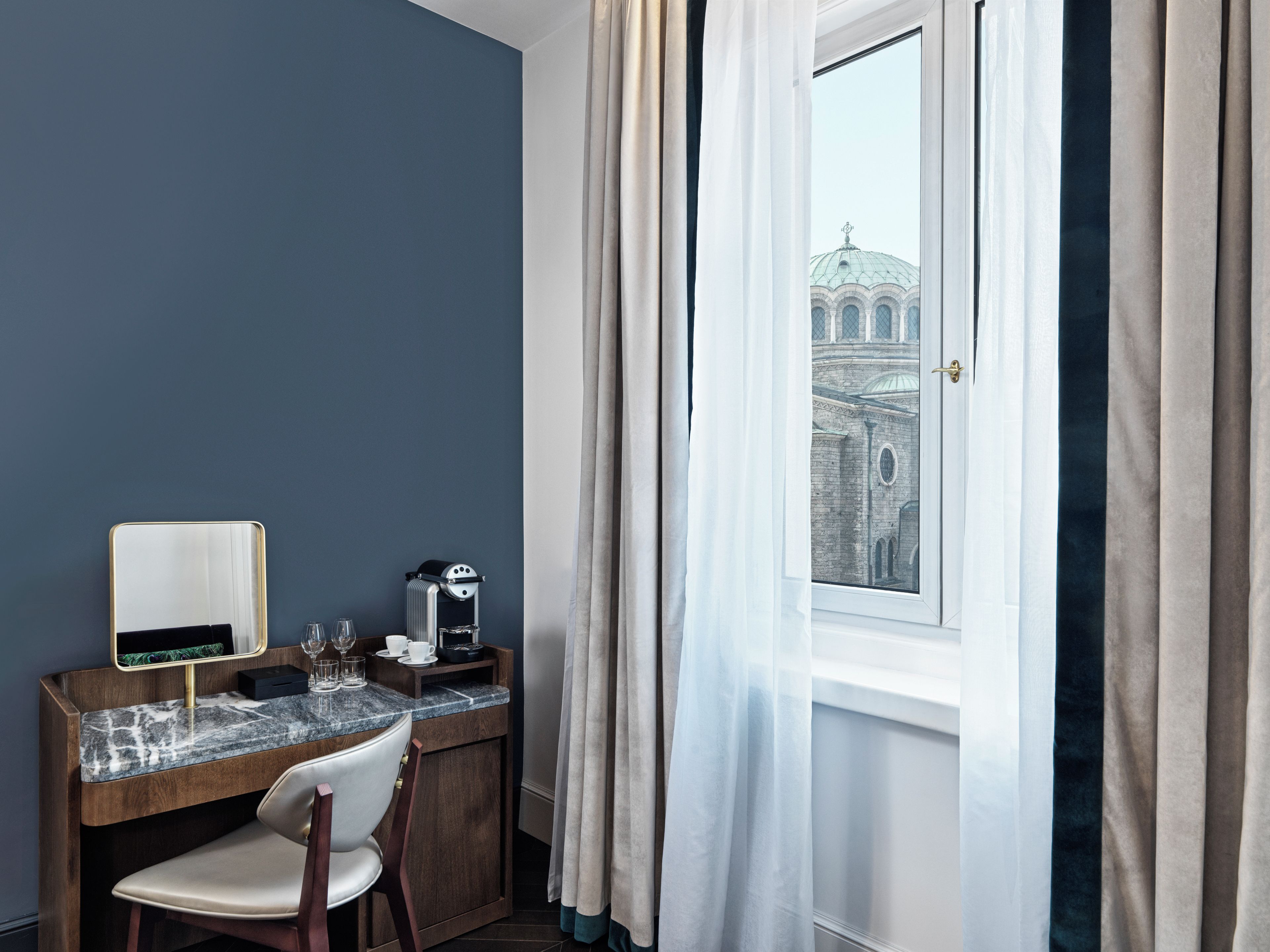 Una habitación con escritorio, silla y ventana con cortinas.