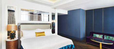 Une chambre d’hôtel avec un grand lit, une table de chevet, une lampe, un canapé et une vue sur l’extérieur.