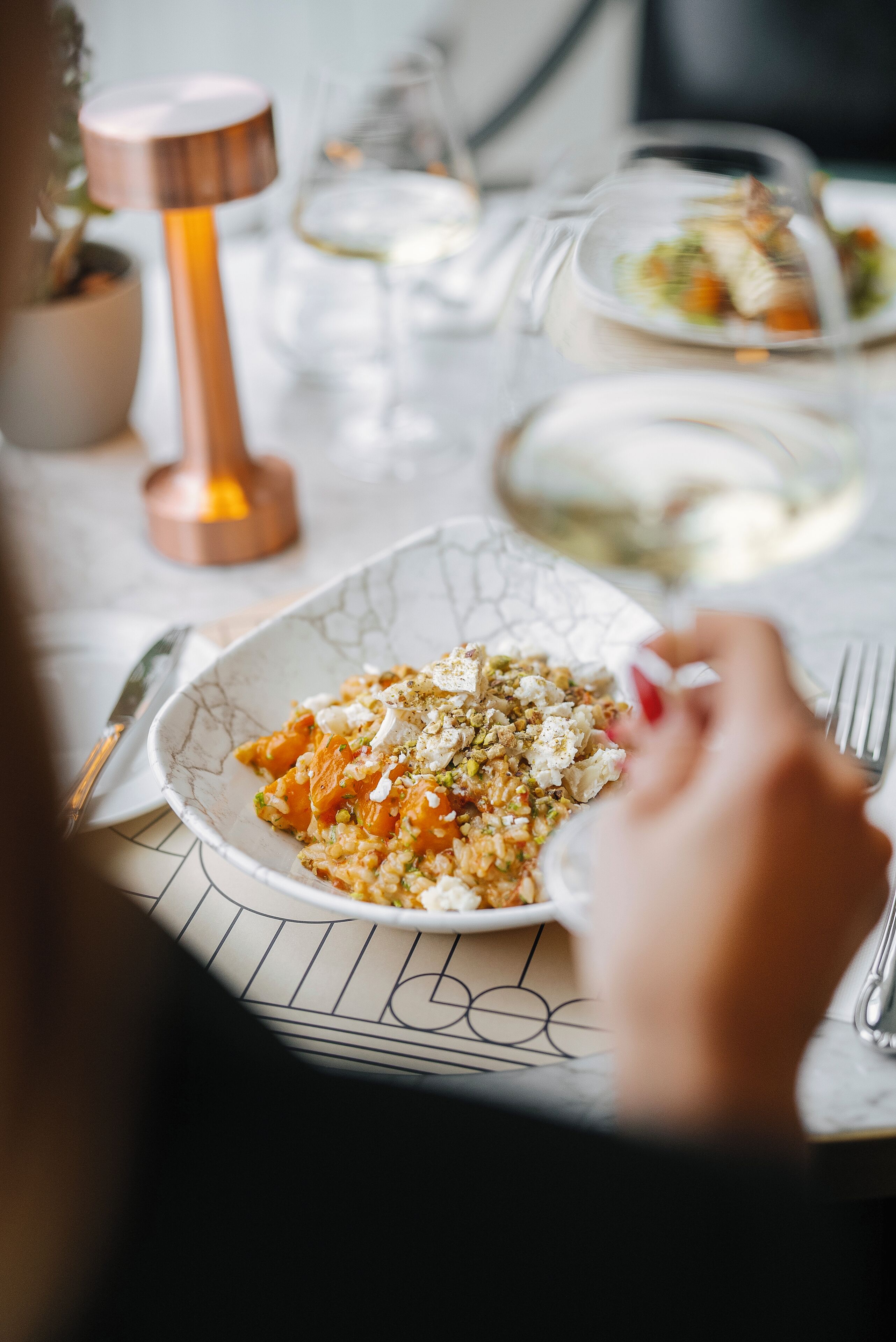 A dining table with a plate of food, a candle, and a glass of water.