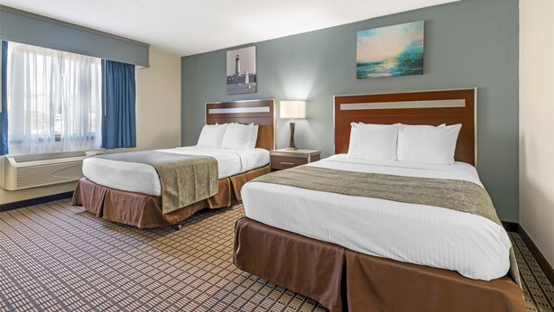 A hotel room with two beds, a window with curtains, a painting on the wall, and a patterned carpet. - Best Western Maritime Inn (Sturgeon Bay)