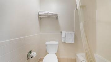 Une salle de bain équipée de toilettes, d’un porte-serviettes et d’un rideau de douche.