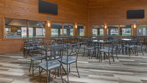 A spacious indoor dining area with wooden walls, multiple tables and chairs, and large windows offering views of the outdoors. - Best Western Maritime Inn (Sturgeon Bay)
