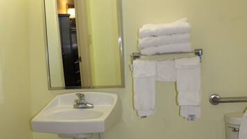 Un baño con lavamanos, espejo, toallero y retrete.