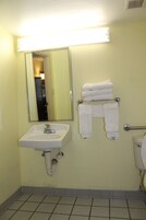 Un baño con lavamanos, espejo, toallero y retrete.
