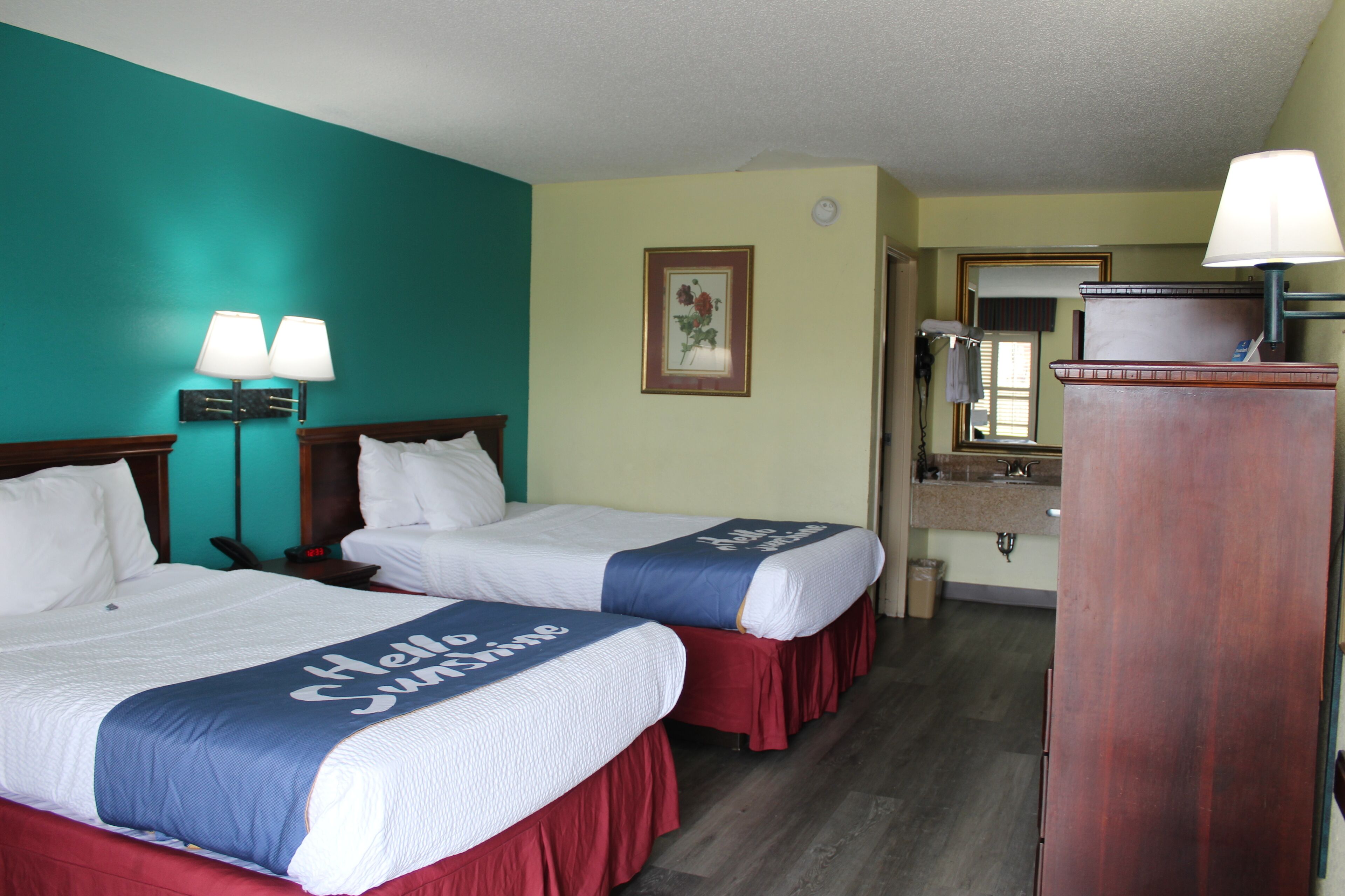 Une chambre d’hôtel avec deux lits, un bureau, un miroir et une commode.
