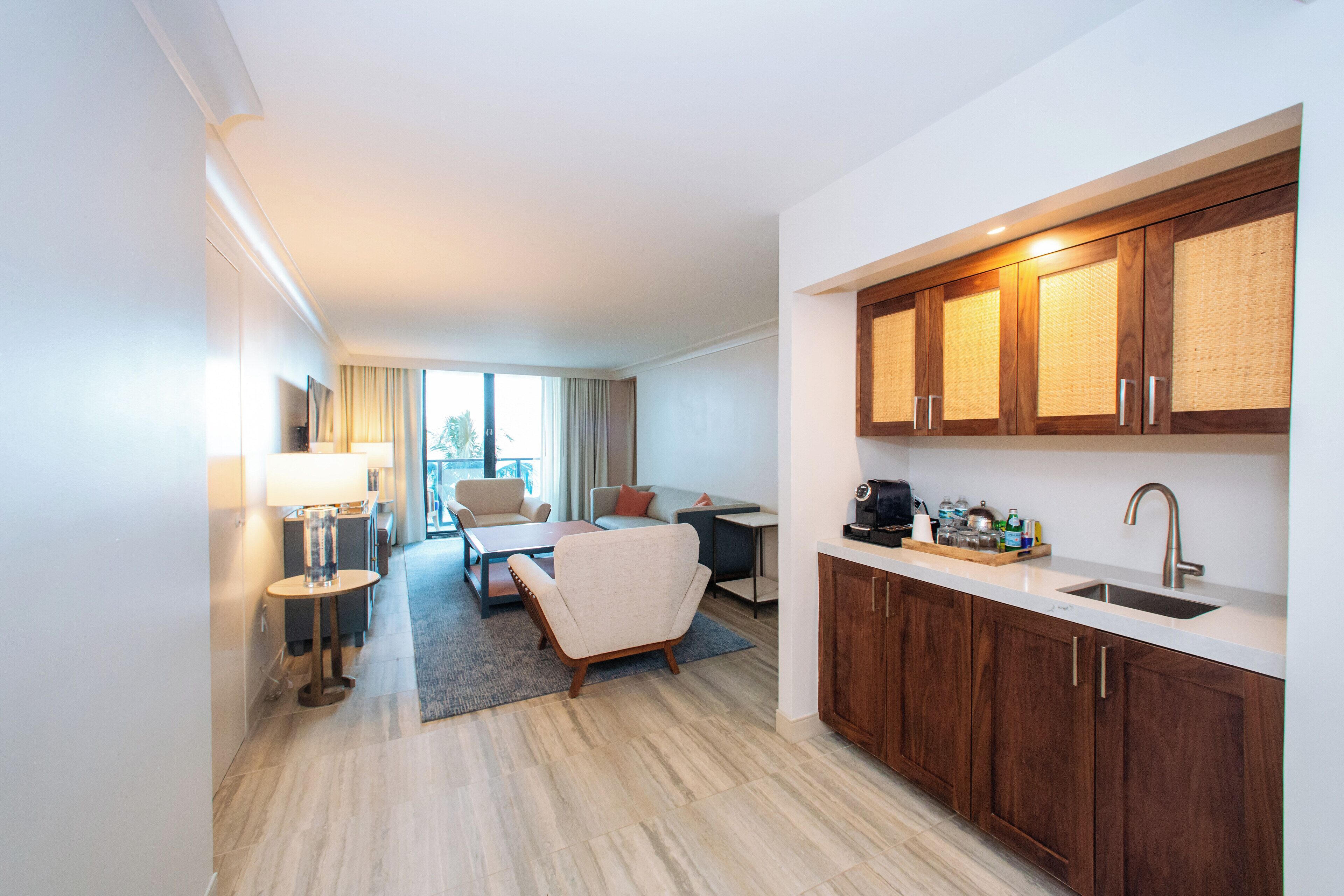 Ein modernes Hotelzimmer mit Küchenzeile, einer Couch, einem Couchtisch und Blick ins Freie.