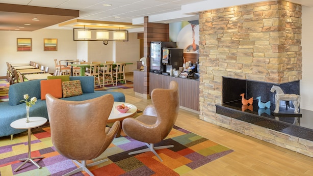 Un vestíbulo de hotel con chimenea de piedra, un comedor con mesas y sillas, y una alfombra colorida.
