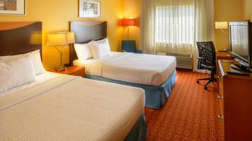 A hotel room with two beds, a desk with a computer, a chair, and a TV.