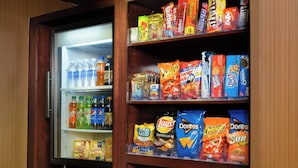 Máquina expendedora con aperitivos y bebidas, un microondas y un refrigerador.