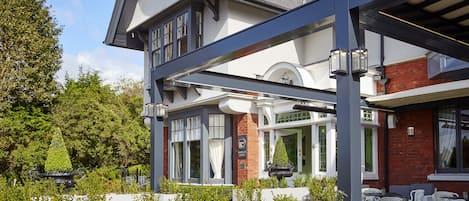 A two-story building with a covered outdoor seating area, a brick facade, and large windows.