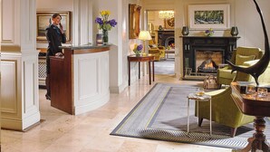 A spacious lobby with a reception desk, a fireplace, and a chandelier.