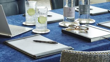 A table with a laptop, a notebook, a pen, glasses, and two bottles of water.