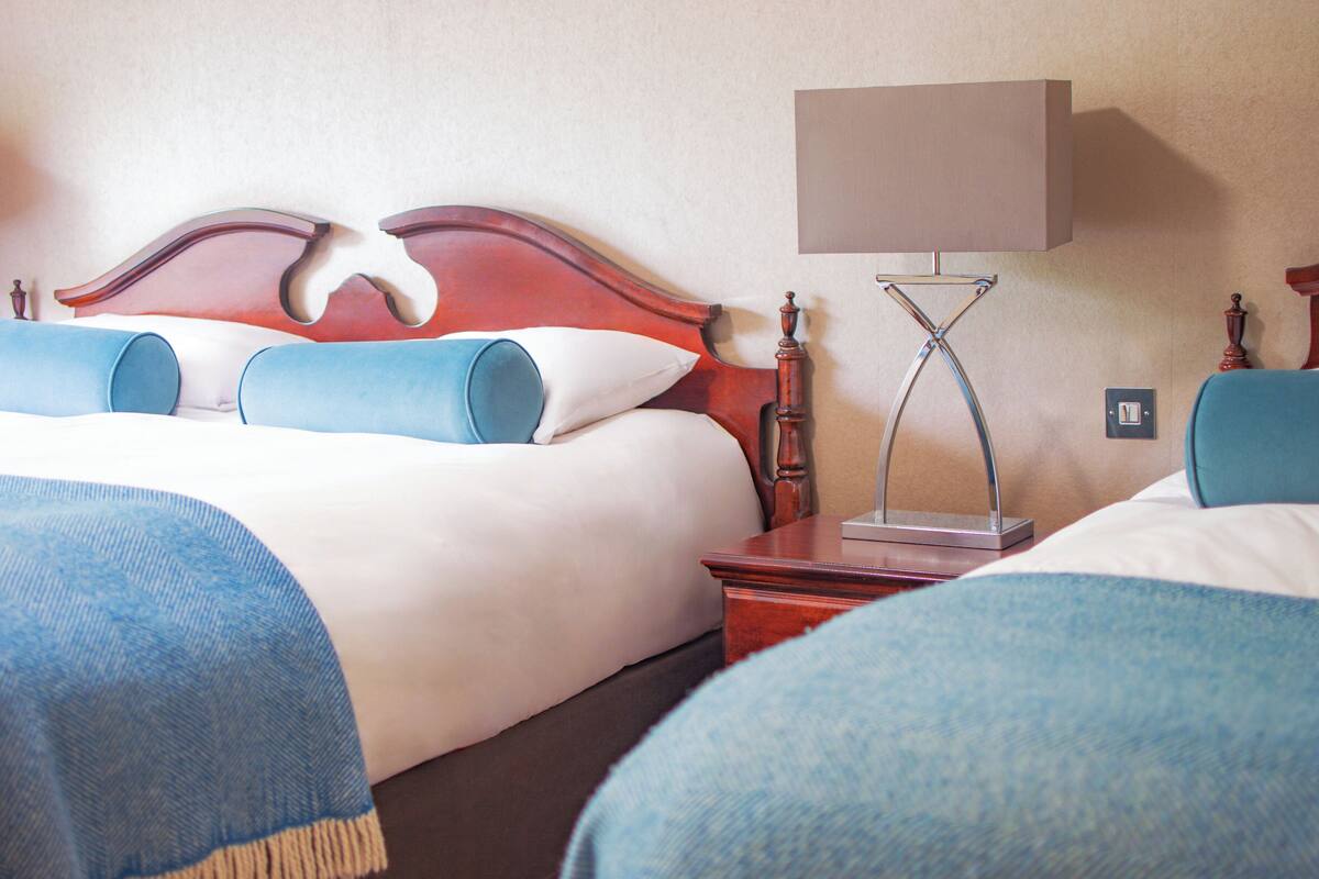 A hotel room with a bed, a nightstand, a lamp, and a wall socket.