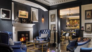 A luxurious living room with leather armchairs, a fireplace, and a bar area.