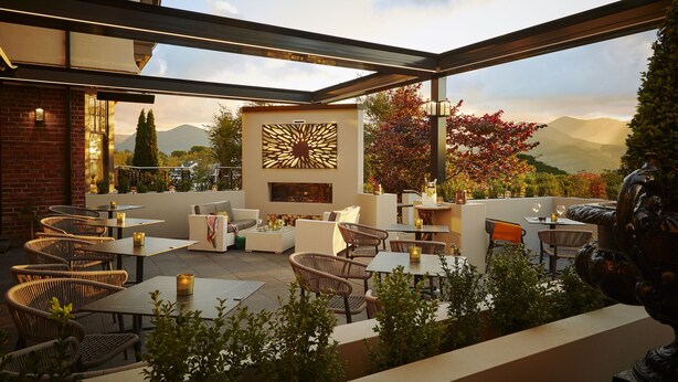 An outdoor patio area with wicker furniture, tables, and a decorative wall.