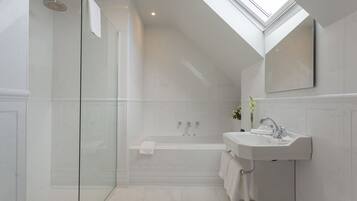 Een moderne badkamer met een douchecabine van glas, een vrijstaand bad en een wastafel met spiegel erboven.