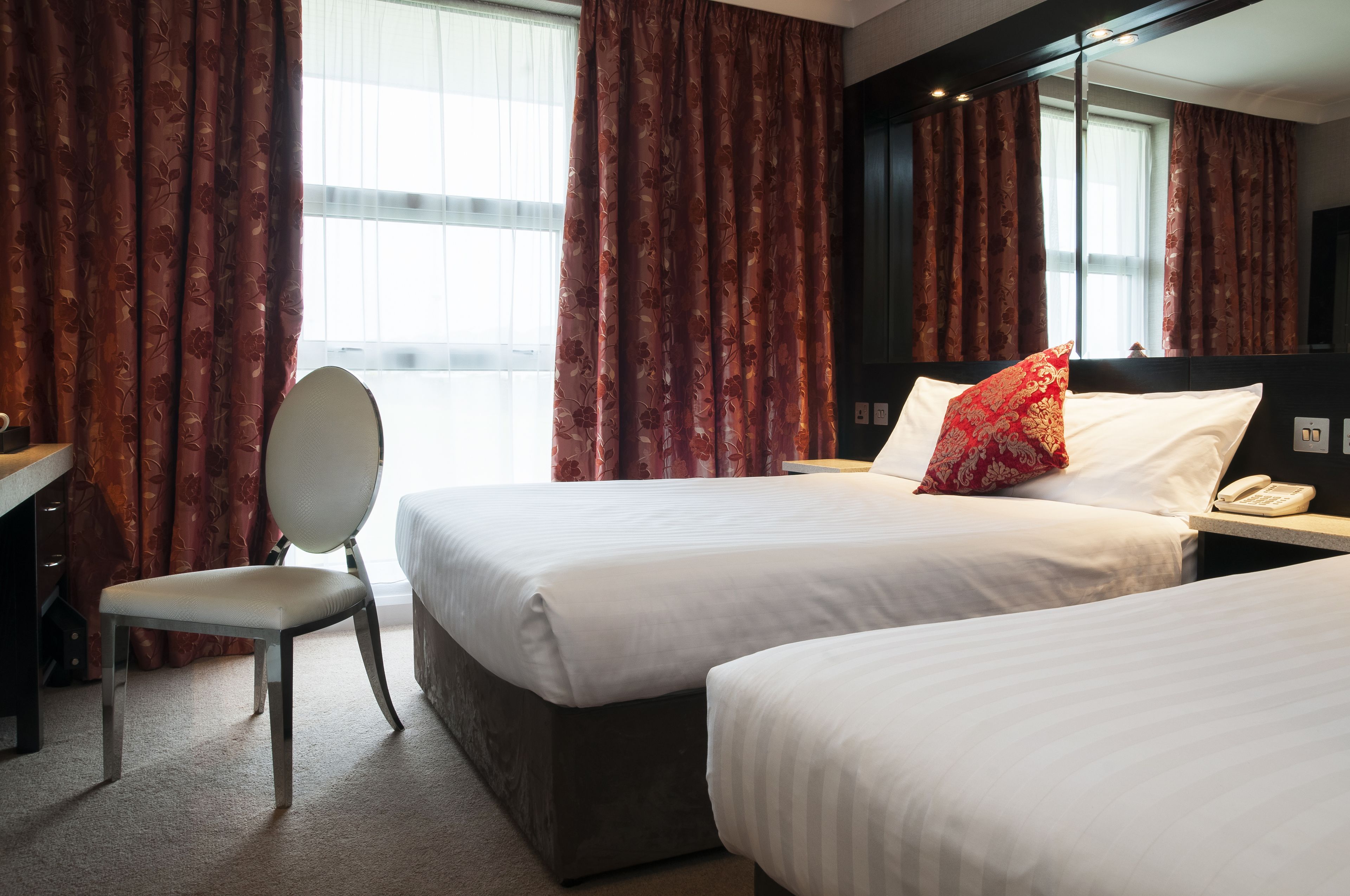 A hotel room with two beds, a desk, and a chair.
