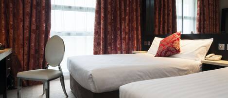 A hotel room with two beds, a desk, and a chair.