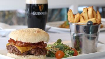 A meal consisting of a burger, fries, and a salad, with a glass of beer in the background.